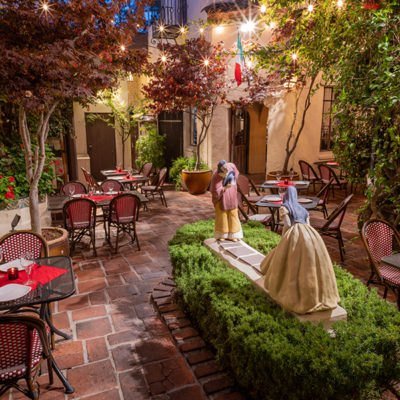 Little Napoli's lantern-lit courtyard with The Greeting statues in the historic El Paseo building