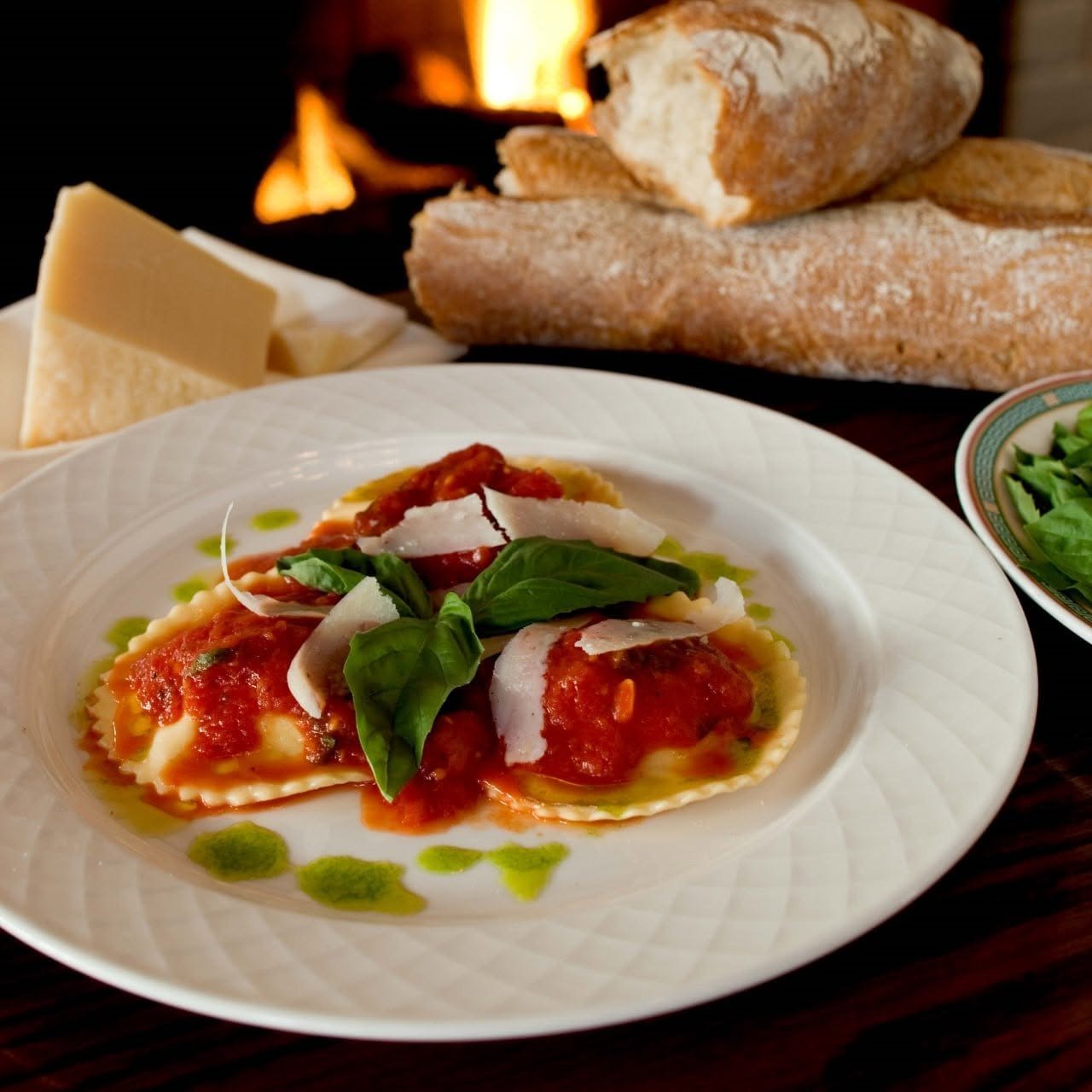 Homemade ravioli with tomato, basil and shaved parmesan by the fireplace