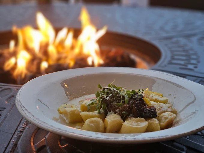Handmade gnocchi plated beside the fire pit at dusk