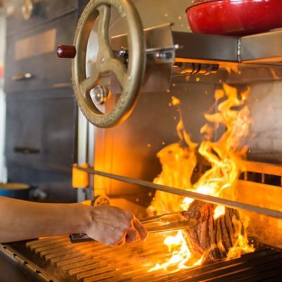 Chef grilling over an open wood fire